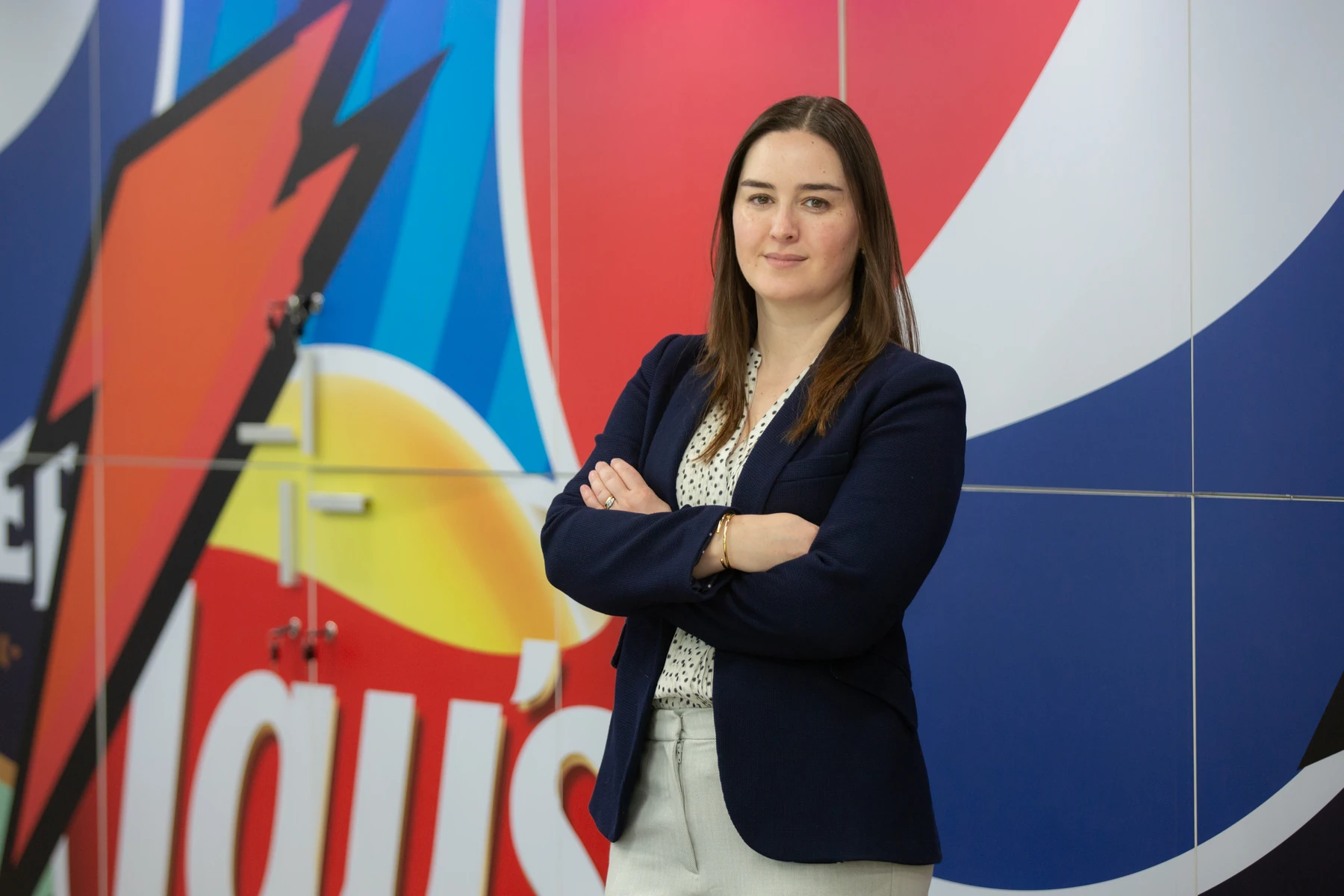 Retrato corporativo con chaqueta azul frente a un mural de PepsiCo